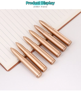 Dettaglio di 6 penne a sfera a forma di proiettile color oro su un taccuino da ufficio