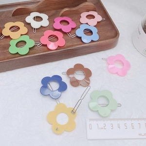 Colorful matte flower hair clips in various pastel colors arranged on a wooden tray