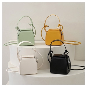 Minimalist PU leather box handbags in green, yellow, beige and black on white stairs