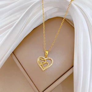 Macro detail of gold double heart pendant necklace with shimmering crystal inlay on silk