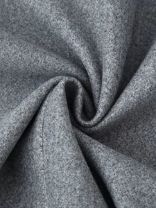 Dettaglio del tessuto grigio in misto lana che mostra la texture morbida e l'orlo con frange