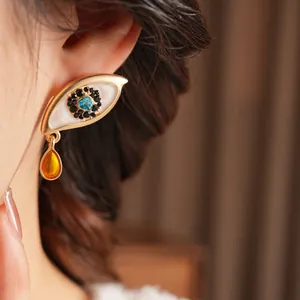 Vintage gold eye earrings with blue pupil and amber waterdrop pendant on model