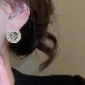 Close-up of a gold-plated earring with black and clear cubic zirconia on the ear