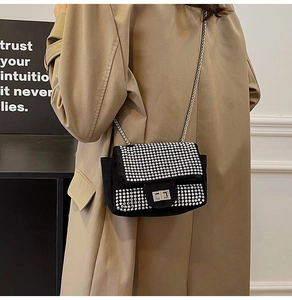 Close-up of black suede crossbody bag with sparkling rhinestones and silver metal lock