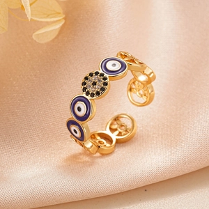 Detail of 18K gold evil eye enamel ring with zircon accents on a beige silk background