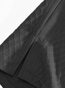 Details des schwarzen Jacquard-Strickstoffs mit Seitenschlitz und Saumverarbeitung