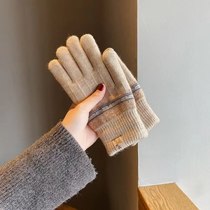 Close-up of beige knitted gloves featuring striped cuffs and warm thermal lining details