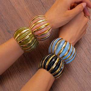 Detail of chunky acrylic bangles with wavy patterns and golden metal stripe accents
