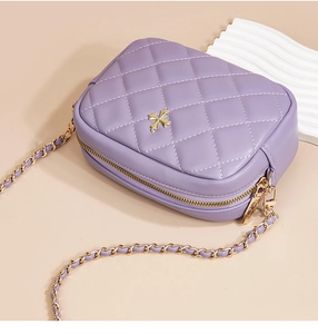 Detail of purple quilted leather crossbody bag with gold cross hardware and chain strap