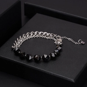 Polished silver cuban chain bracelet with faceted black onyx beads on a jewelry box