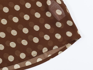 Détail du tissu en mousseline à pois marron avec étiquette d'entretien de lavage
