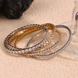 Close-up of four stackable 18K gold and silver plated tennis bracelets with sparkling zircons
