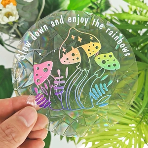Detail of holographic mushroom suncatcher sticker with slow down and enjoy the rainbows text