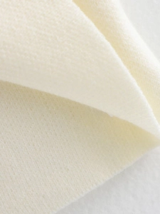 Primer plano macro del tejido de punto crema mostrando la textura suave y fibras finas