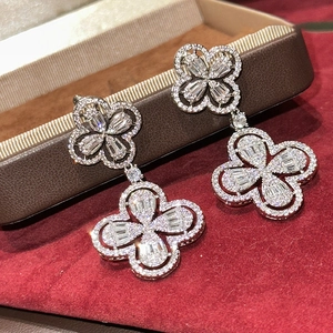 Macro shot of silver clover drop earrings with brilliant pavé crystals on red velvet