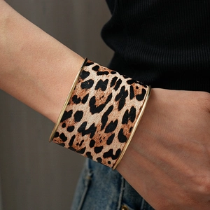 Close-up of leopard print wide open cuff bracelet with gold metal edges on a wrist