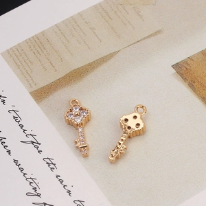 Close-up of gold plated key charms with cubic zirconia inlay on vintage paper background