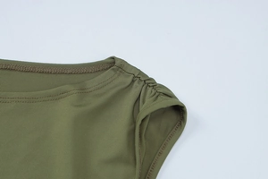 Detail des olivgrünen Kleides mit Schulterfalten und feinen Nähten auf dem Stoff