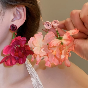 Macro view of fabric flower earrings with deep red petals and beaded tassels