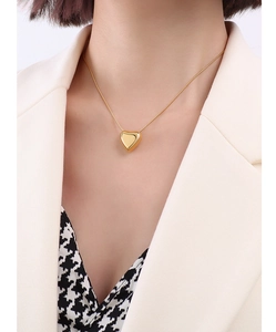Detailed close-up of a gold heart pendant necklace on a model showing the mirror finish