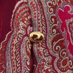 Gros plan d'un bouton métallique doré sur un tissu imprimé à motifs cachemire