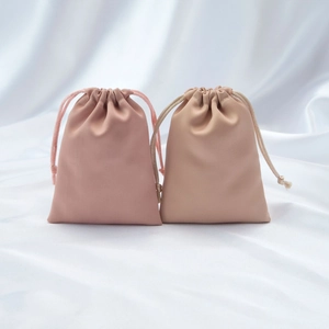 Detail view of satin drawstring jewelry pouches in dusty pink and light coffee colors