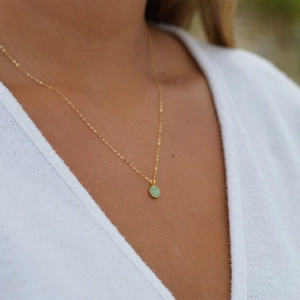 Close-up of a minimalist gold sterling silver necklace with a turquoise pendant on a model