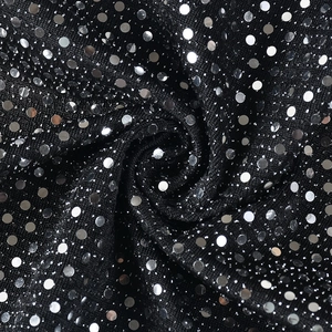 Vue macro d'un tissu noir avec paillettes argentées montrant texture et drapé