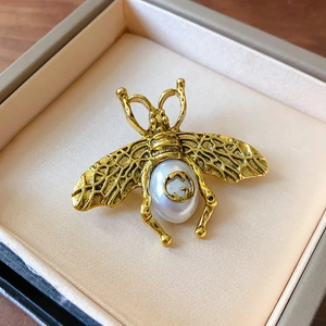 Detailed macro view of a vintage bee brooch with pearl and signature GG logo engraving