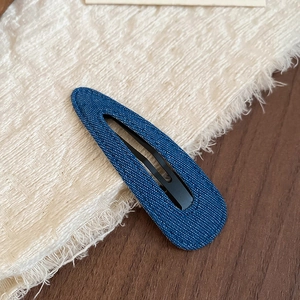 Detail of blue denim fabric hair clip showing texture and metal snap structure