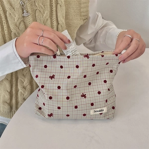 Detail view of large capacity makeup bag with red polka dots and bow pattern being filled