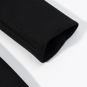 Gros plan sur la texture du tissu en laine noire et le revers de la manche de ce manteau