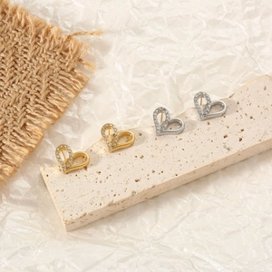 Détail de boucles d'oreilles en cœur avec zircons brillants sur un support en pierre