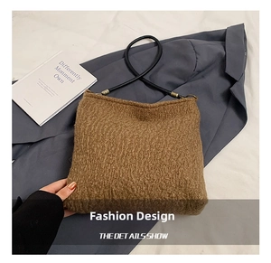 Detail showing the brown faux shearling texture and black leather strap of the bucket bag