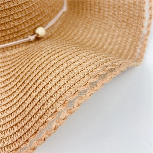 Close-up of hand-woven straw hat brim with hollow wave lace edge and wooden bead detail