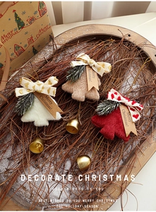 Three plush Christmas tree pendants with metal bells on a rustic wooden tray decoration