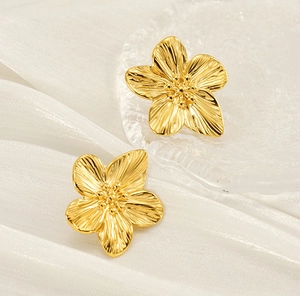 Dettaglio di orecchini a fiore in acciaio dorato 18K con texture spazzolata