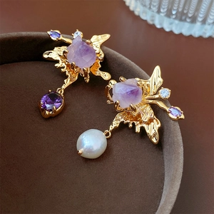 Macro shot of asymmetric earrings with freshwater pearls and purple amethyst stones