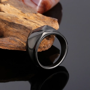 Macro shot of minimalist black geometric faceted ring on natural wood with reflection