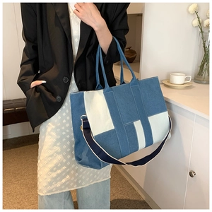 Detail of patchwork denim tote bag featuring blue color blocks and wide strap