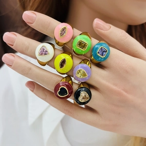 Close-up of colorful enamel heart rings with gold finish and zircon stones on fingers