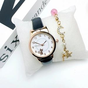 Close-up of cat-eared watch with black leather strap and star moon charm bracelet