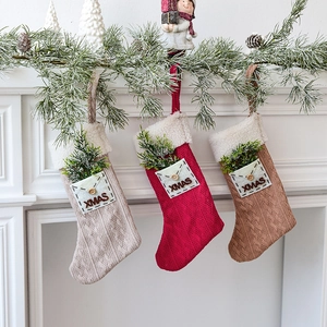 Three knitted Christmas stockings in red, beige and brown hanging on a white fireplace