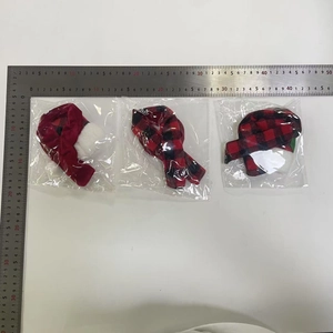 Three Christmas pet hats in red, white and plaid patterns displayed on a measuring ruler
