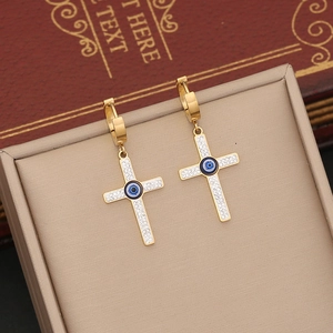 Gold hoop earrings with iced cross pendant and blue evil eye detail on jewelry display