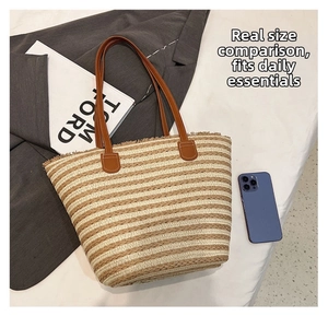 Close-up of large woven straw tote bag with striped pattern and leather handles