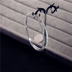 Close-up of oversized silver hoop earrings with sparkling rhinestones on jewelry stand