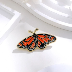 Macro detail of enamel monarch butterfly brooch with gold plating and vibrant textures