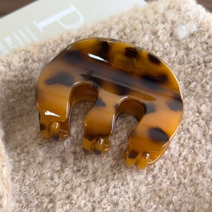Macro view of amber tortoiseshell hair claw clip on soft beige plush fabric