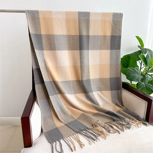 Detail of soft beige and grey plaid scarf with decorative fringe on a chair